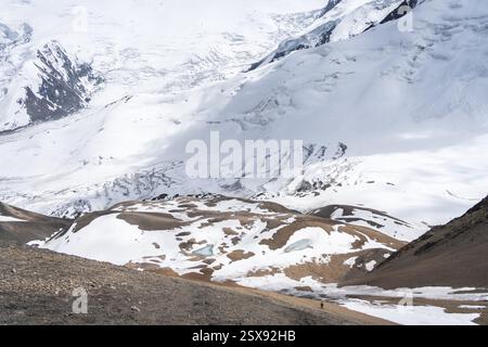 Weite Aufnahme eines einsamen winzigen Wanderers in einer riesigen alpinen Gletscherlandschaft, Pamir Mountains, Kirgisistan. Stockfoto