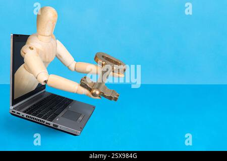 Hölzerne Schaufensterpuppe, die von einem Laptop-Bildschirm auftaucht und einen goldenen Schlüssel auf blauem Hintergrund bietet, Stockfoto