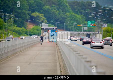 Daejeon, Südkorea - 28. Mai 2021: Radfahrer fahren auf dem speziellen Radweg auf der North Star Road, der durch Leitplanken vom Autobahnverkehr getrennt ist. Stockfoto