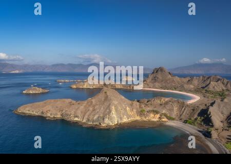 Dieser atemberaubende Blick aus der Luft zeigt die felsigen Padar Inseln, die von atemberaubend klarem türkisfarbenem Wasser umgeben sind, alles unter einem klaren blauen meer Stockfoto