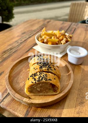 Hausgemachter Dorset Apfel und Wurstbrötchen serviert mit Chips und Meersalz Stockfoto