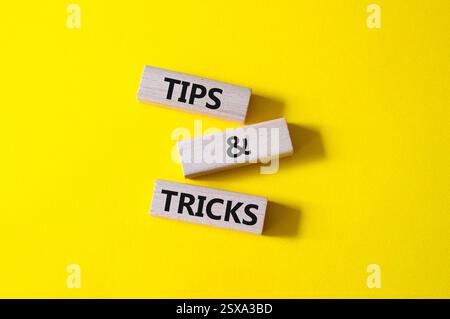 Symbol für Tipps und Tricks. Holzblöcke mit Worten Tipps und Tricks. Schöner gelber Hintergrund. Geschäftskonzept und Tipps und Tricks. Kopierbereich. Stockfoto