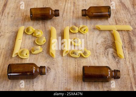 Das Wort Diät mit verschiedenen Nudelsorten auf einem Holzbrett geschrieben Stockfoto