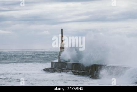 Riesige Wellen stürzen während des Wintersturms über Breakwater ab Atlantische Wellen waschen den Leuchtturm am Praia da Aguda Sandstrand in der Siedlung Aguda nahe P Stockfoto