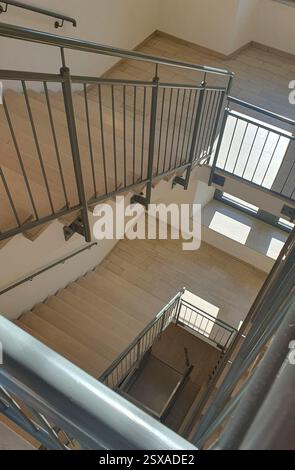 Innentreppe mit Marmorsteintreppe in Beige im Gebäude und Metallgeländer. Nahaufnahme der Spirale. Stockfoto