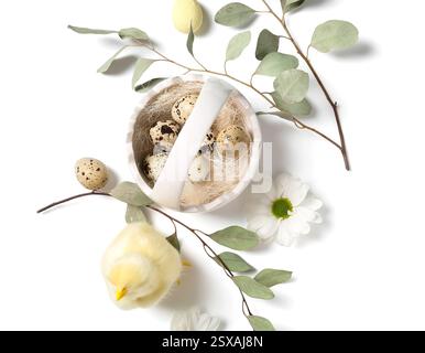 Korb mit Osterwachteleiern, Hähnchen, Kamillenblüten und Eukalyptuszweigen auf weißem Hintergrund Stockfoto