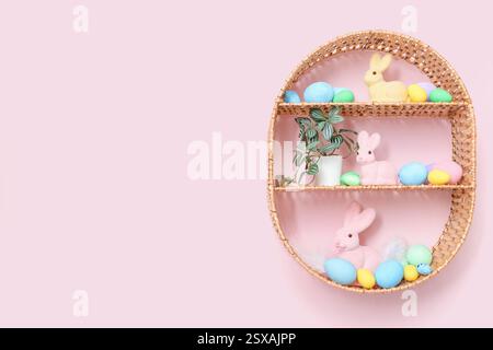 Korbregal mit Osterdekorationen, die an der pinken Wand im Wohnzimmer hängen Stockfoto
