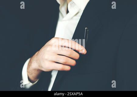 Geschäftsmann, der einen Stift aus der Tasche holt Stockfoto