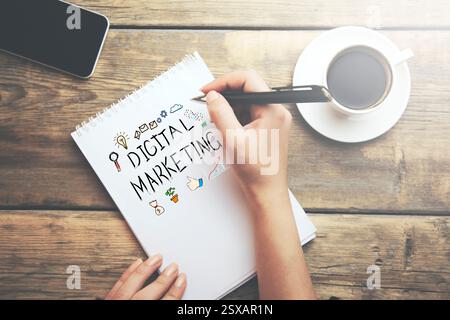 Frau schrieb digitalen Marketingtext auf Notizblock auf dem Desktop Stockfoto