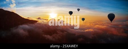 Heißluftballons fliegen über Berge und Wolken bei Sonnenuntergang Stockfoto