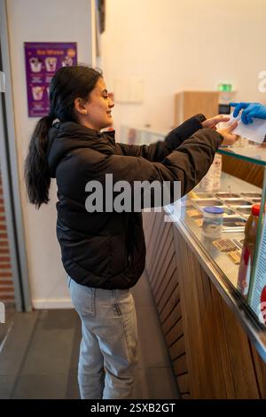 Die Kundin erhält ihre Quittung, nachdem sie einen gefrorenen Joghurt in der Eisdiele gekauft hat Stockfoto