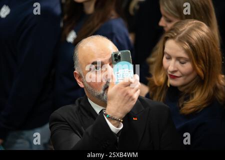 Berlin, Deutschland, 23. februar, Unterstützer zeichnet die CDU-Wahlveranstaltung mit einem Smartphone-Aufkleber „Team Merz“ auf. Stockfoto