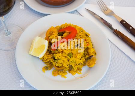 Paella mit Garnelen, Pfeffer, Gemüse und Zitrone auf Platte Stockfoto