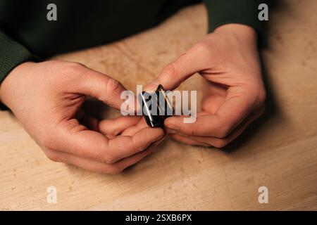 Draufsicht des Technikers, der die Batterie der Smartwatch mithilfe spezieller Werkzeuge sorgfältig auswechselt, wodurch der komplizierte Prozess der modernen Gerätereparatur hervorgehoben wird. Stockfoto