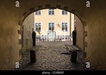 Eine berühmte Touristenattraktion, das Schwedische Tor in Rigas Altstadt, Lettland, durch eine historische Kopfsteinpflasterpassage zu einem sonnendurchfluteten Innenhof wi Stockfoto