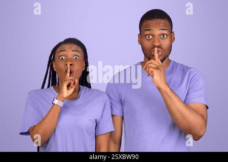 Schwarzes Paar, das Finger auf die Lippen stampft und ein Zeichen für die Stille macht Stockfoto