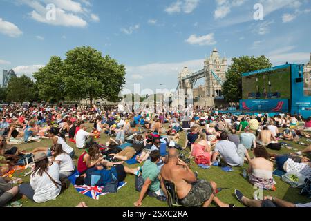 Eine große Menschenmenge, die ein Sportereignis beobachtet, wahrscheinlich mit dem Fahrrad, im Potters Fields Park in der Nähe der Tower Bridge in London. Ein großer Bildschirm zeigt die Aktion an. Stockfoto