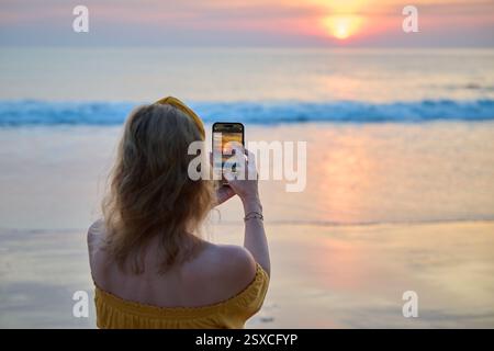 Frau, die auf ihrem iPhone Fotos von einem wunderschönen Sonnenuntergang macht Stockfoto