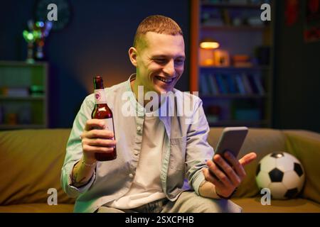 Porträt eines lächelnden Mannes, der Smartphone und Getränke hält Stockfoto