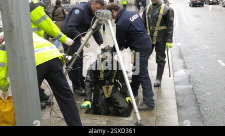 Dublin, Irland - 11. April 2013 - Ein Garda-Offizier in Gefahrenanzügen und Gasmaske führt während der irischen Präsidentschaft der Europäischen Union 2013 eine Sicherheitsräumung einer Kanalisation vor Dublin Castle in der Dame Street durch. Stockfoto