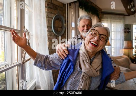 Glückliche reife Frau, die mit ihrem älteren Mann zu Hause tanzt, aktives gesundes Seniorenpaar Stockfoto