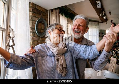 Glückliche reife Frau, die mit ihrem älteren Mann zu Hause tanzt, aktives gesundes Seniorenpaar Stockfoto