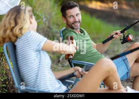 Frau und Mann trinken ein Bier beim Angeln am See Stockfoto
