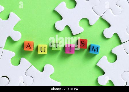 Wort Autismus gemacht mit bunten Würfeln und Puzzleteilen auf grünem Hintergrund, flache Lay Stockfoto