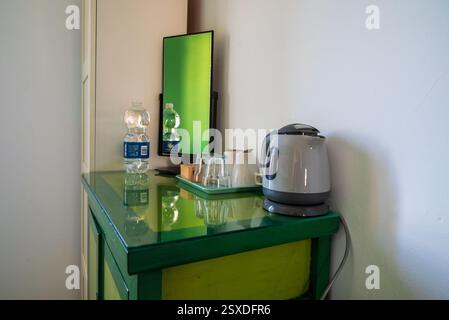 Malaga, Spanien, 27. Dezember 2024 Wasser, Gläser und Wasserkocher auf einem grünen Tisch in einem Hotelzimmer in einer alten spanischen Villa Stockfoto