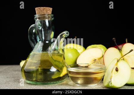 Apfelessig in einer Glasessig-Schüssel zwischen Äpfeln Stockfoto