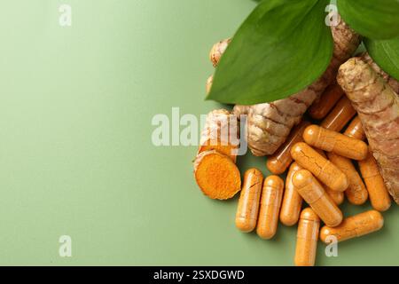 Kurkuma-Rhizome und -Kapseln auf grünem Hintergrund, flache Lagen. Leerzeichen für Text Stockfoto