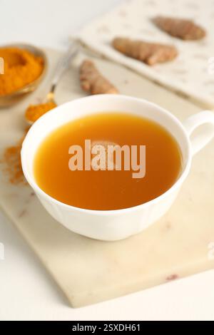 Aromatischer Kurkuma-Tee, Pulver und Rhizome auf weißem Tisch, Nahaufnahme Stockfoto