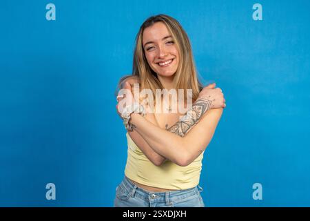 Glückliche junge Frau umschließt sich selbst, zeigt Selbstliebe und Selbstvertrauen Stockfoto
