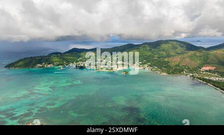 Luftdrohne mit lebhafter grüner Küste, sanften Hügeln und kristallklarem türkisfarbenem Wasser. Praslin, Seychellen. Stockfoto