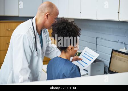 Arzt bespricht Krankenversicherungsoptionen mit medizinischem Personal im Büro Setting Stockfoto