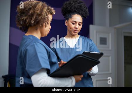 Medizinisches Fachpersonal, das Patienten-Datensätze in einem klinischen Umfeld diskutiert Stockfoto