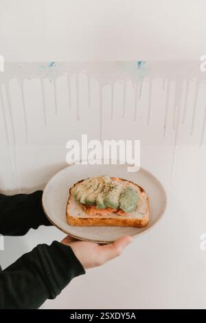 Avocadotoast mit geräuchertem Lachs, serviert auf einem Teller im Café-Ambiente Stockfoto