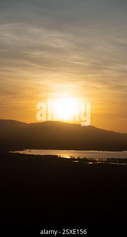 Erleben Sie einen atemberaubenden Sonnenuntergang, der die ruhigen Hügel und das Wasser im atemberaubenden Colors Lake Manyara Tansania Afrika zeigt Stockfoto
