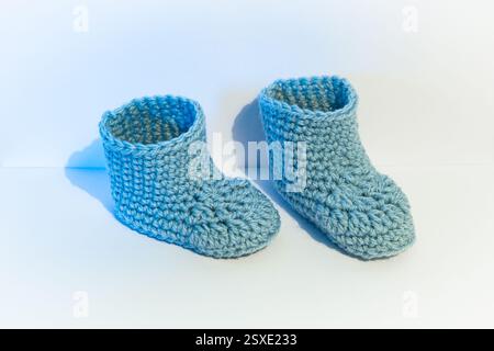 Ein Paar hellblaue und gehäkelte Babysocken auf weißem Hintergrund Stockfoto