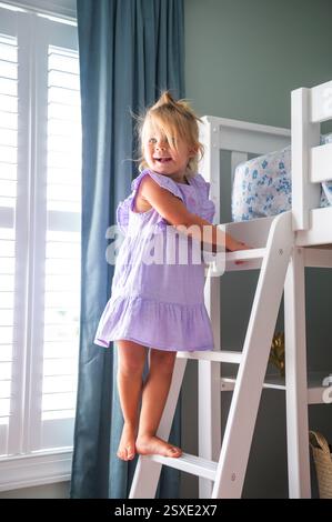 Blondes Mädchen Kleinkind klettert Etagenbett Leiter in ihrem Kinderschlafzimmer Stockfoto