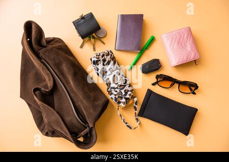 Flache Grundausstattung mit Wildledertasche auf pastellfarbenem Hintergrund Stockfoto