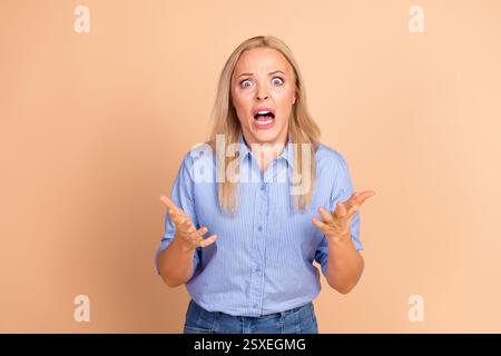 Überraschte Geschäftsfrau, die Schock und Verwirrung auf beigefarbenem Hintergrund ausdrückt Stockfoto