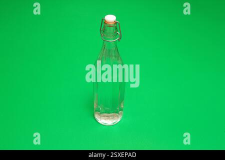 Studio-Aufnahme einer transparenten Glasflasche mit klarer Flüssigkeit vor einem leuchtend grünen Hintergrund Stockfoto