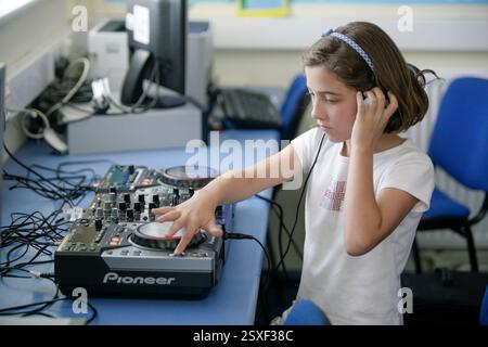 Ein Schulmädchen, das in einem Klassenzimmer einer britischen Schule DJ lernt Stockfoto