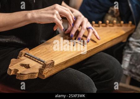 Die Finger eines Mädchens, das Kännchen spielt, ein litauisches Streichinstrument, das zur Familie der Baltischen Zitherer gehört, bekannt als Baltische Psalter Stockfoto