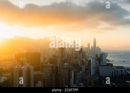 Atemberaubender Sonnenuntergang über der Skyline von Hongkong, der einen warmen goldenen Glanz über dem Victoria Harbour und den endlosen Wolkenkratzern ausstrahlt. Stockfoto