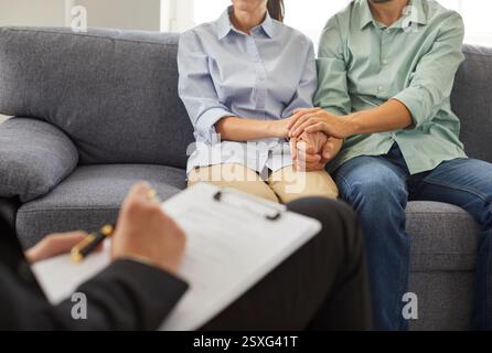 Psychologe macht Notizen während der Therapiesitzung mit jungen Paaren, die an Beziehungsfragen arbeiten. Stockfoto
