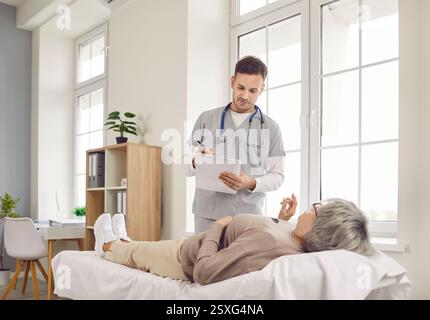 Ältere ältere grauhaarige Patientin, die während der Untersuchung in der Arztpraxis auf der Couch liegt. Stockfoto