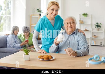Glückliche Krankenschwester umarmt einen älteren Mann im Hospiz, Porträt Stockfoto