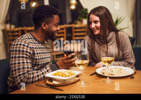 Zwei Freunde essen im Restaurant. Sie verwenden ein Smartphone. Stockfoto
